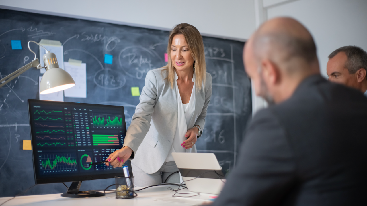 Company employees discussing market data on charts. Skilled woman leader and two men looking at diagrams on computer screen analyzing profit growth. Business growth and female business leaders concept