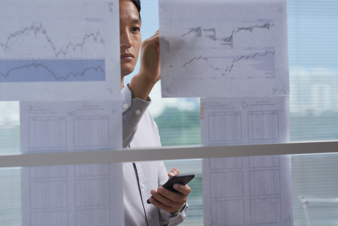 Businessman taking notes on financial charts hanging on the wall